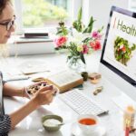Femme prenant un petit-déjeuner sain devant son ordinateur pour trouver des solutions bien-être au quotidien sans dépasser son budget.