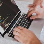 Personnes tapant sur un clavier d'ordinateur portable avec graphique coloré à l'écran