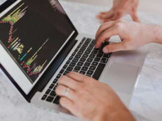 Personnes tapant sur un clavier d'ordinateur portable avec graphique coloré à l'écran