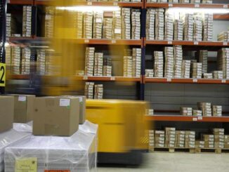 Un chariot jaune déplace des palettes de cartons dans un entrepôt