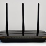 Un routeur Wi‑Fi noir à trois antennes posé sur fond blanc