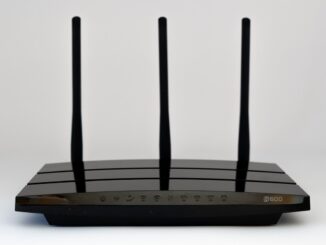 Un routeur Wi‑Fi noir à trois antennes posé sur fond blanc