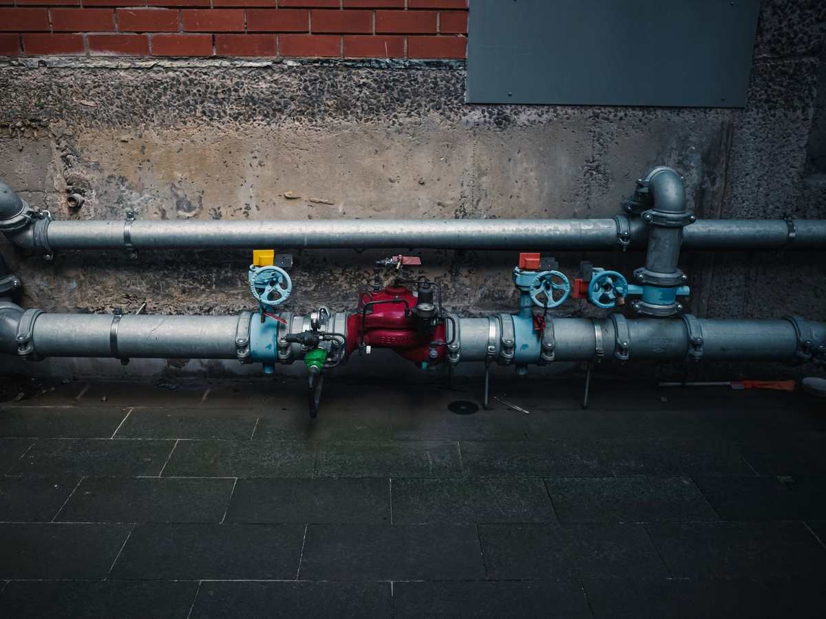 Industrial pipes with valves and gauges installed on a concrete wall Industrial pipes with valves and gauges installed on a concrete wall