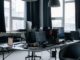 Un bureau moderne avec plusieurs écrans, chaises et lumière naturelle