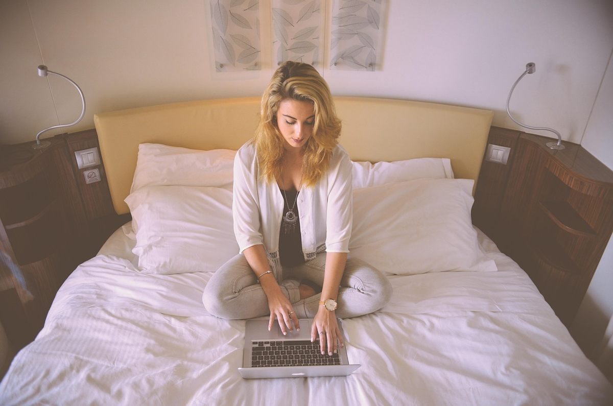 Femme sur un lit avec un ordinateur portable Femme sur un lit avec un ordinateur portable